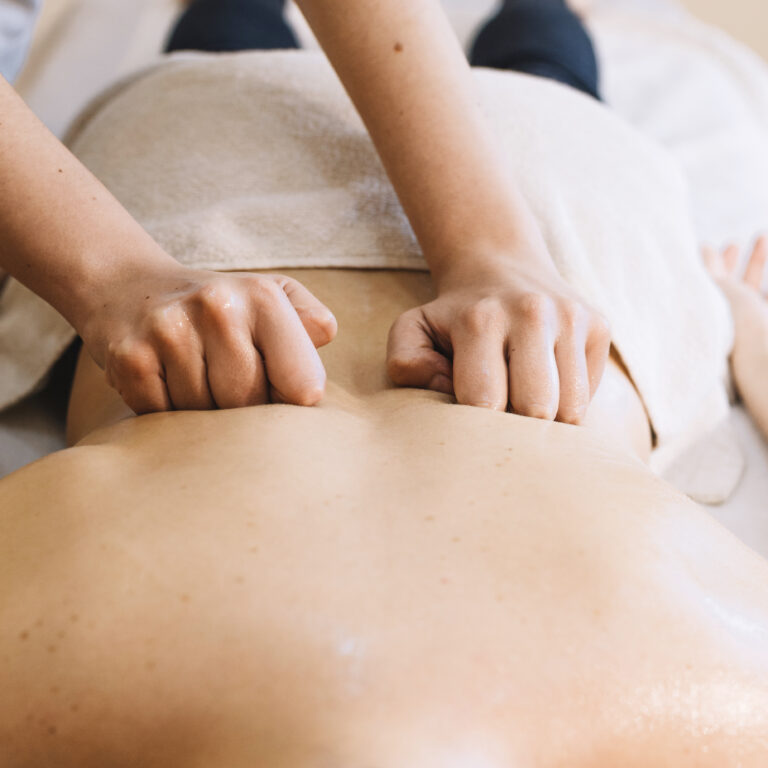 Ruhige Massagesituation mit Handtüchern, Öl und warmer Atmosphäre.