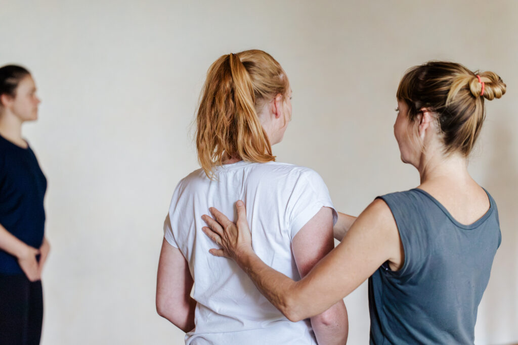 Pilates-Trainerin gibt einer Teilnehmerin in einer Gruppe eine Haltungsanleitung